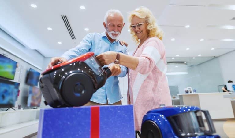 可爱的白人夫妇选择新的真空吸尘器为他们的家。科技商店内部。